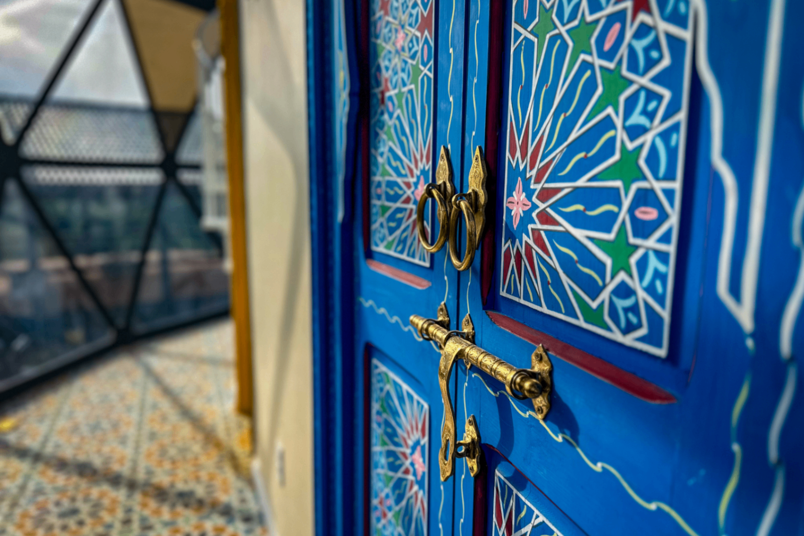 A blue medina door with brass handles, hand-carved and set into Moroccan tile